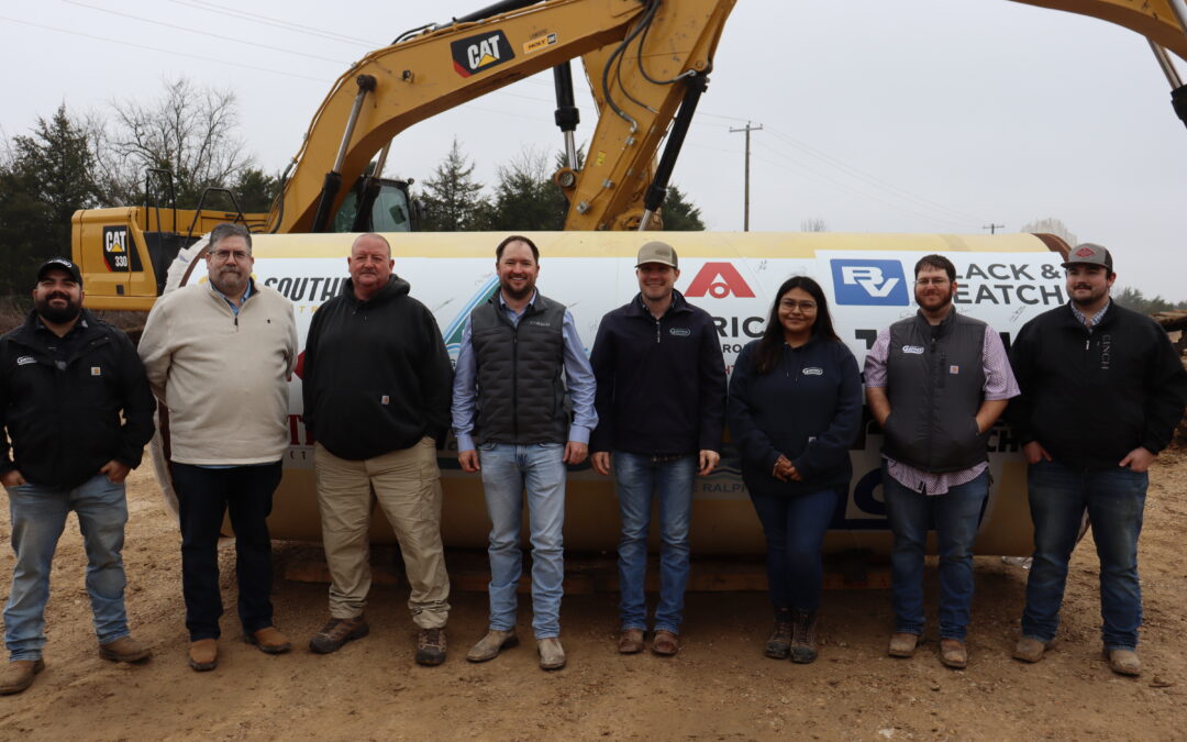 Upper Trinity team members, contractors and city/county officials pose in front of last piece of pipe with logos of all participants February 2025
