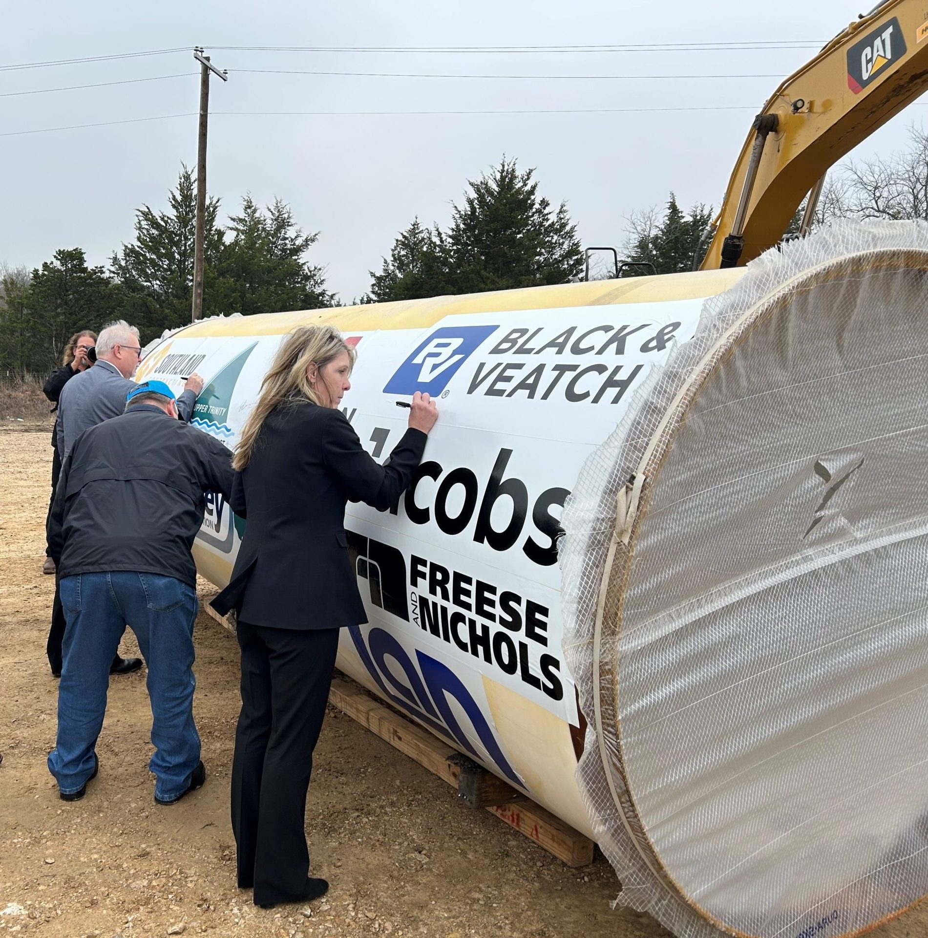 Team members sign commemorative piece of pipeline