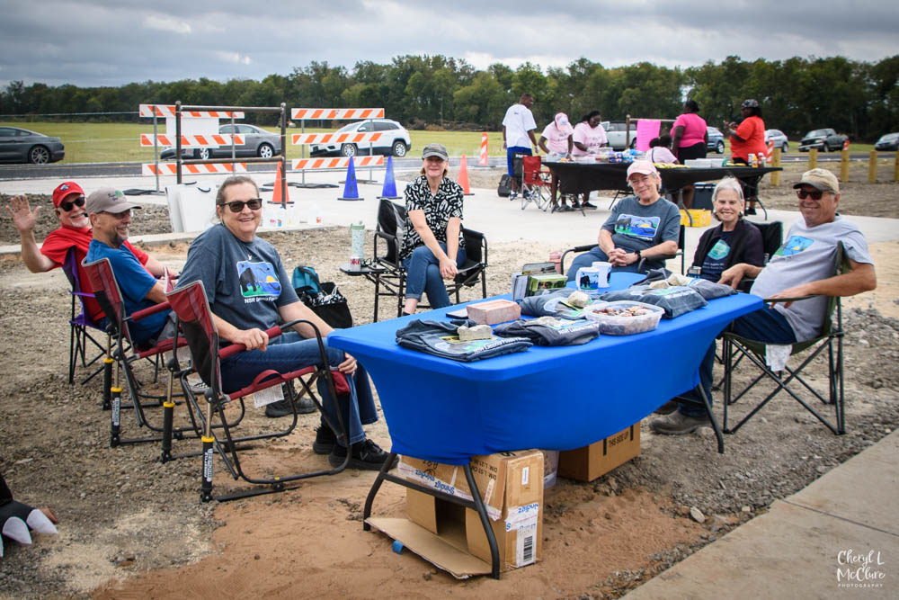 Fossil Park celebration photo - people sit at tables of fossil displays at the new park.